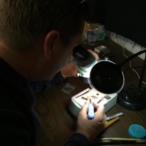 Conservator looking through a microscope to remove corrosion on an artifact