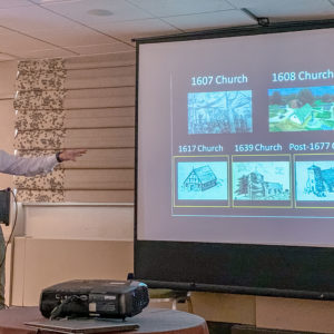 Man presenting and gesturing to images on a projected slide