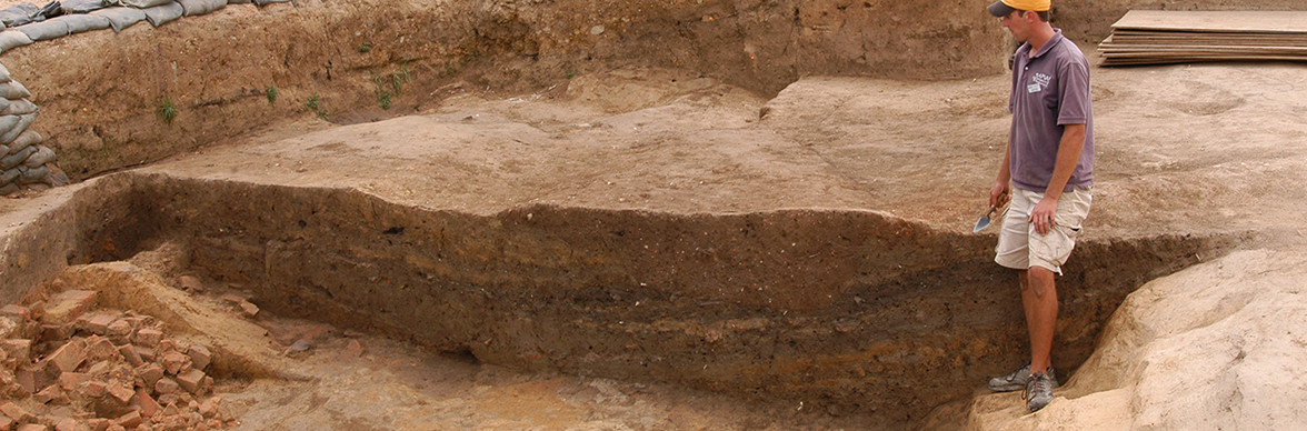 Archaeologist examining excavation unit