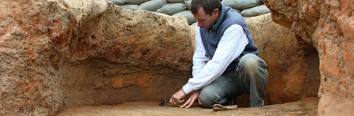 Archaeologist troweling in excavation unit