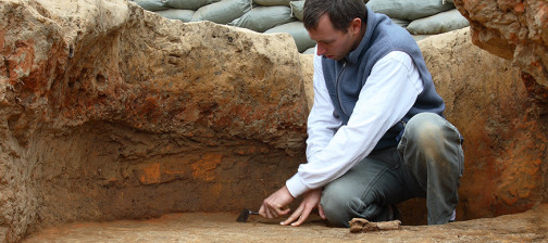 Archaeologist troweling in excavation unit