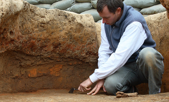 Archaeologist troweling in excavation unit