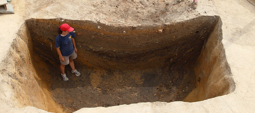 Archaeologist standing in deep excavation unit