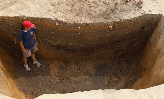 Archaeologist standing in deep excavation unit