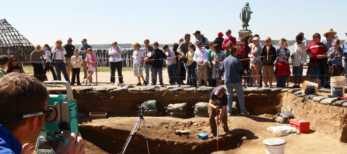 Archaeologist records unit with total station while another talks to a large group