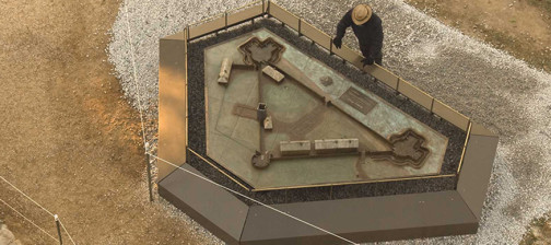 Aerial view of archaeologist looking at a model of James Fort