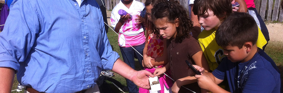 Staff shows artifact to visiting children