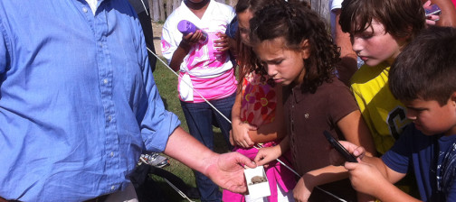 Staff shows artifact to visiting children