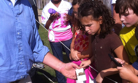 Staff shows artifact to visiting children