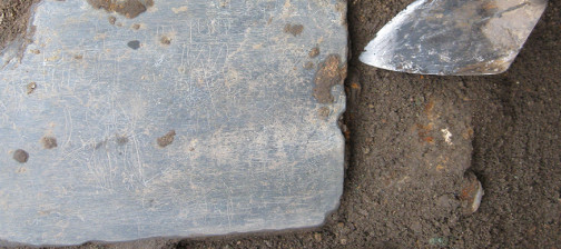 Slate tablet lying in situ next to trowel