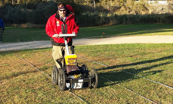 man pushes a ground penetrating radar unit along a transect line