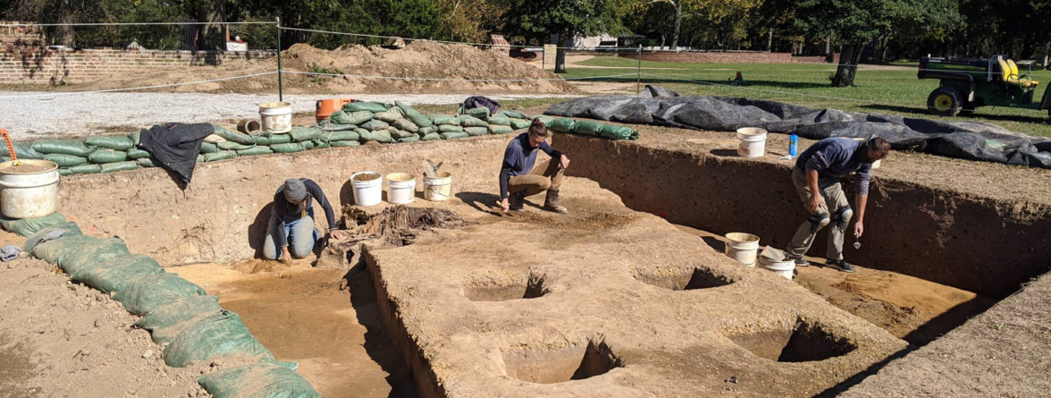 three archaeologists excavating in a large unit