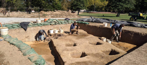 three archaeologists excavating in a large unit