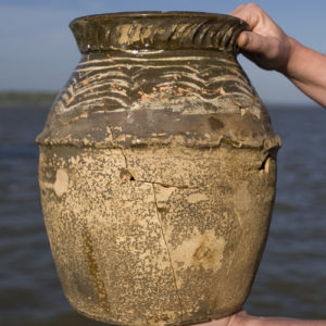 Hands holding mended pot in front of river