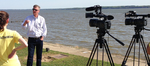 Crew filming a man standing on a riverbank