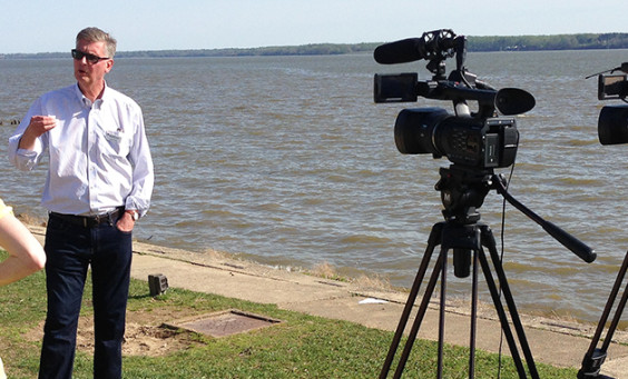 Crew filming a man standing on a riverbank