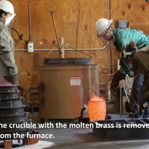 Two workers remove molten brass from furnace