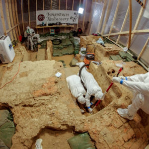 Suited archaeologists excavate in clean room