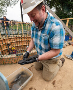 Archaeological Conservator Dr. Chris Wilkins examines the  just-excavated leather shoe sole.