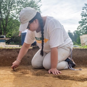 Development Assistant Korinne Young carefully trowels away south of the Archaearium during one of the staff dig days.