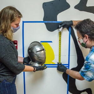 Curator Leah Stricker and Conservator Dr. Chris Wilkins work on a mock-up of the "Gentleman Soldiers" exhibit with a contemporaneous close helm.