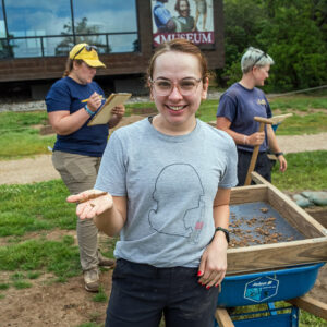 Director of Communications & Marketing Angel Johnston holds a nail she found while screening through material on one of the staff dig days.