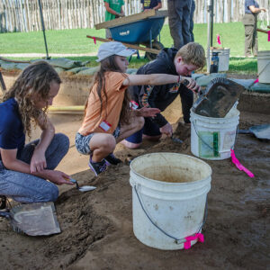 Three campers excavate the plowzone at the cellar site. The soil they place in the buckets will be screened by other kids over wheelbarrows (at rear of photo) to look for artifacts.