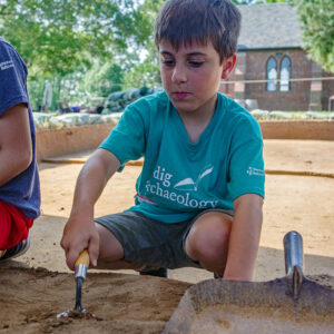A camper trowels away at the cellar site. The Memorial Church can be seen behind him.