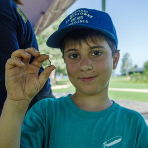 A camper holds a shard of glass he found while screening.