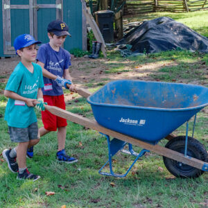 Two campers return a wheelbarrow after dumping screened soil.