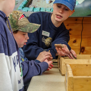 Natalie shows two young visitors a fragment of a ceramic.