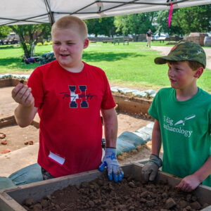 Campers examine an artifact found while screening soil.