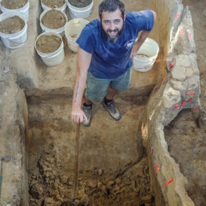 Archaeologist stands in excavated unit