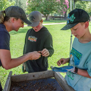 Archaeological Field Technician Katie Griffith helps campers look for artifacts during the screening process.