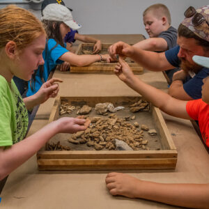 Kids sort through artifacts found at the cellar site in June. Archaeological Field Technician Josh Barber helps the campers identify tricky ones.