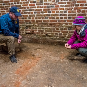 Two archaeologists examine earth floor