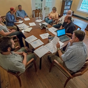 Group sits around a table with papers