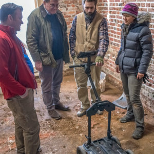 Four people examine data on the camera of a mobile ground penetrating radar unit