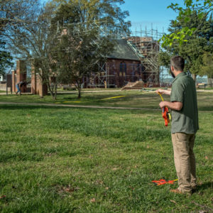 two people laying out a transect line in a grassy area using a long tape measure