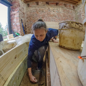 Site Supervisor Anna Shackelford excavates the area where the concrete footings for the glass floor will be installed.