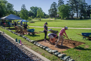 Field school students and staff excavate their squares in front of the Archaearium museum.