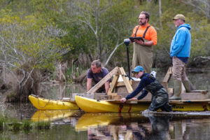 A GPR survey of a portion of the Pitch and Tar Swamp in search of archaeological features. The GPR antenna is stationed aboard an improvised catamaran. (Clockwise from left) Staff Archaeologist Gabriel Brown, Dr. David Leslie of TerraSearch Geophysical, Director of Archaeology David Givens, Staff Archaeologist Natalie Reid.