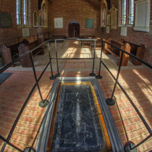 Church interior with refinished floor, installed tombstone, and wooden pews