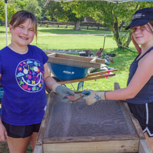 Two kids hold xxx they found while screening soil from the cellar excavations.