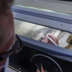 conservator working on a backplate in an air abrasion tank