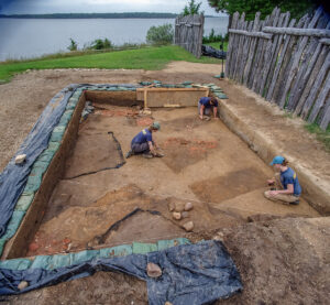 Archaeological Field Technicians Ren Willis and Hannah Barch, and Staff Archaeologist Natalie Reid work in the area of the forthcoming burial excavations. The burials are the dark rectangles each archaeologist is troweling.