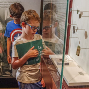 A camper examines some of the small finds in the Archaearium's Gentleman Soldiers exhibit.