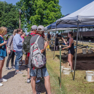 Field school student Ellie Taylor discusses the excavations with visitors.