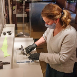 Curator Leah Stricker arranges the barrel, lock, and cock from snaphaunce pistols for the "Gentleman Soldiers" exhibit