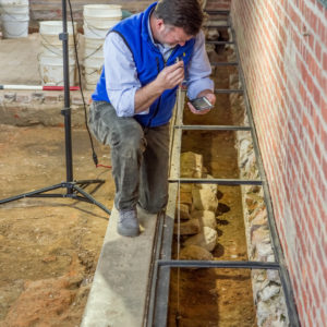 Archaeologist measuring features with plumb bob